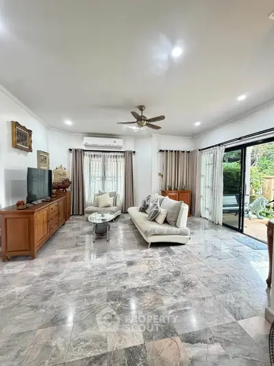 Spacious living room with modern decor and large windows opening to a garden view.