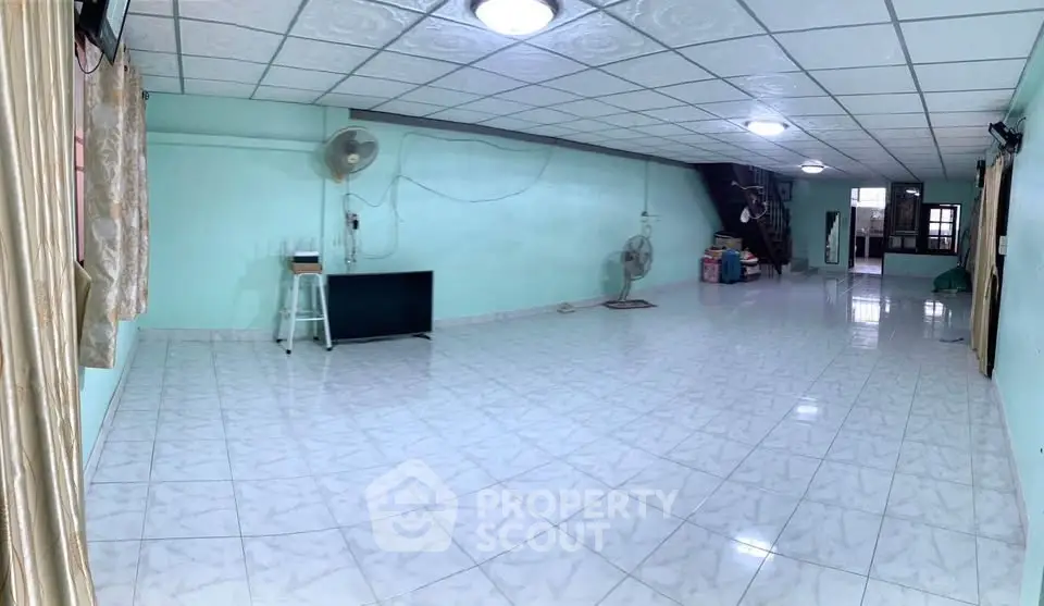 Spacious open-plan living area with tiled flooring and ceiling fans