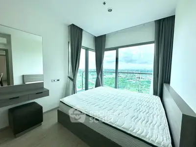 Spacious bedroom with panoramic windows offering stunning views, featuring modern furnishings and ample natural light.