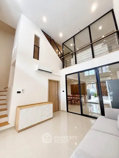 Modern living room with high ceiling and glass balcony overlooking dining area
