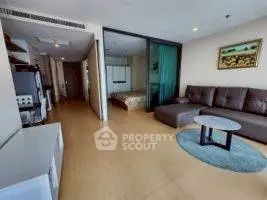 Spacious living room with modern decor and adjacent bedroom in open-plan apartment.