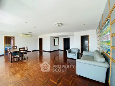 Spacious living room with wooden flooring and modern furniture in a bright apartment.