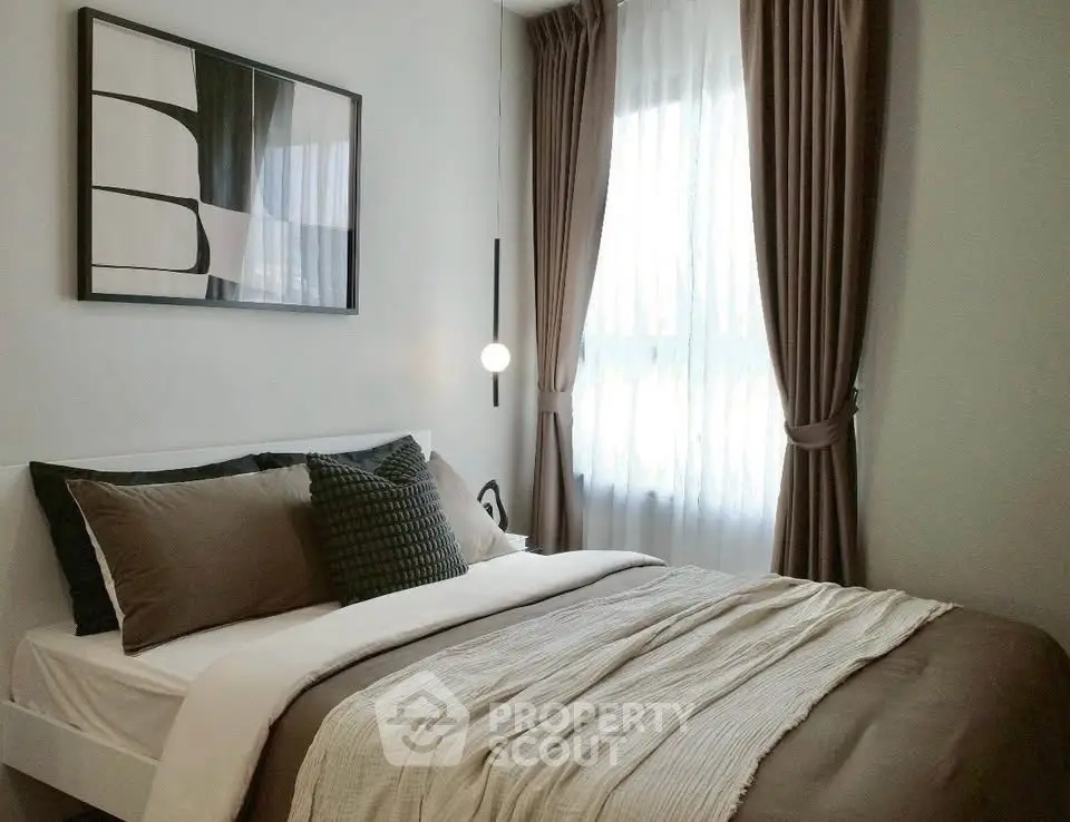 Cozy bedroom with modern decor and natural light through large windows.