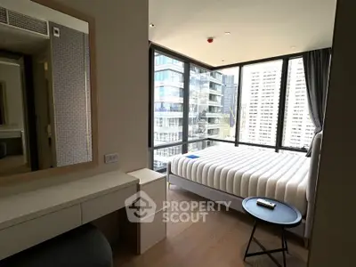 Modern bedroom with floor-to-ceiling windows offering stunning city views in a high-rise building.