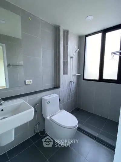 Modern bathroom with sleek gray tiles and large window