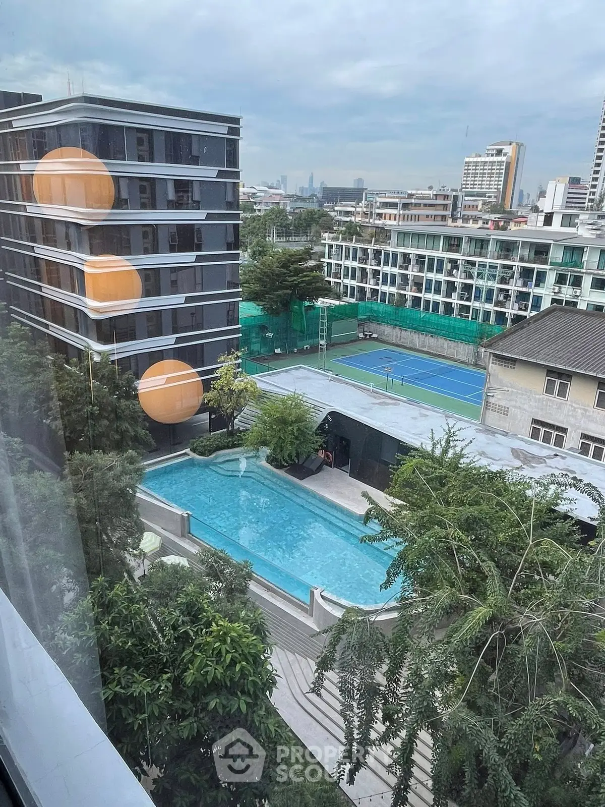 Stunning urban view with pool and tennis court in modern residential complex.