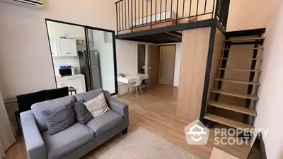 Chic modern apartment featuring a cozy living area with a comfortable sofa, sleek wooden flooring, and a unique mezzanine level accessed by a stylish staircase, creating a spacious and versatile living space.