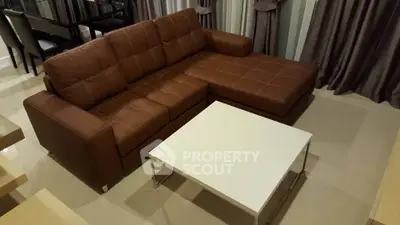 Modern living room with stylish brown leather sectional sofa and sleek white coffee table.