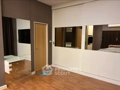 Spacious modern bedroom with wooden flooring and mirrored accents