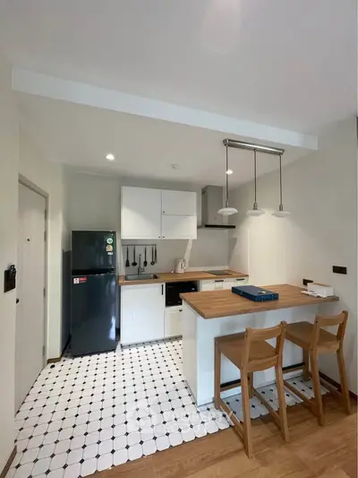 Modern kitchen with open layout, sleek black fridge, and stylish breakfast bar seating.