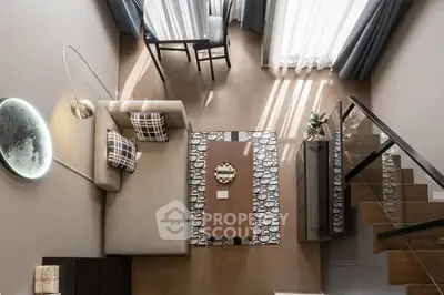 Modern living room with stylish decor and natural light, featuring a cozy sofa and elegant staircase.