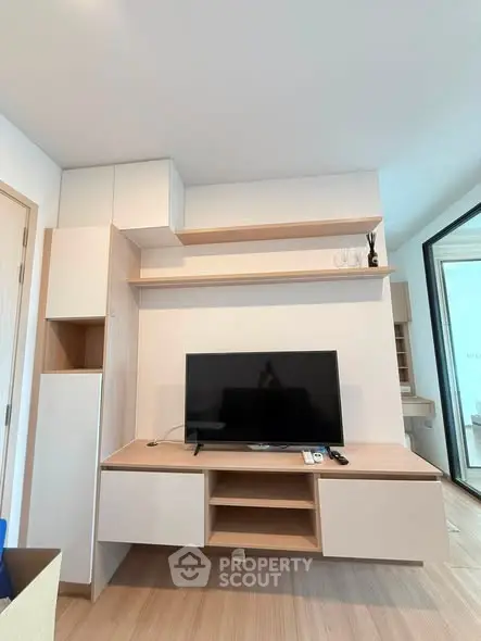 Modern living room with sleek TV unit and open shelving, showcasing minimalist design and natural light.