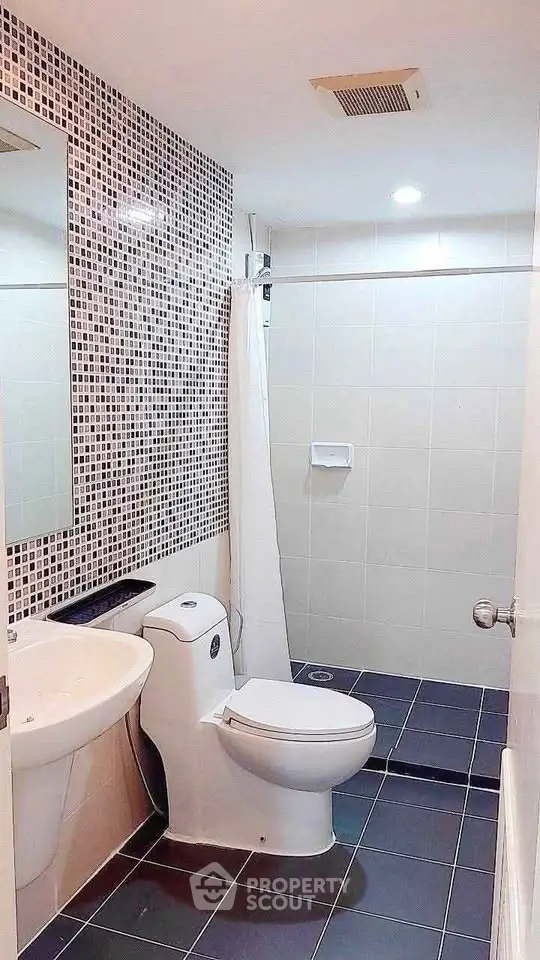 Modern bathroom with sleek design and tiled walls, featuring a shower and toilet.