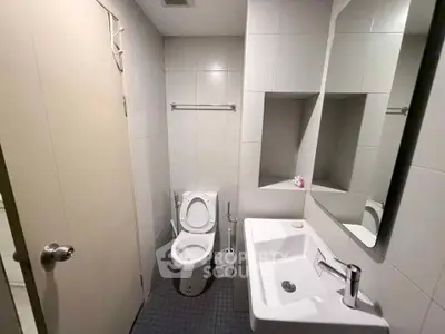 Modern bathroom with sleek fixtures and minimalist design, featuring a toilet and sink.