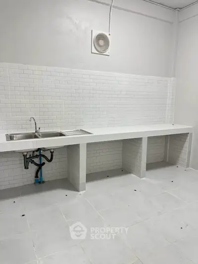 Minimalist kitchen with white tiles and stainless steel sink