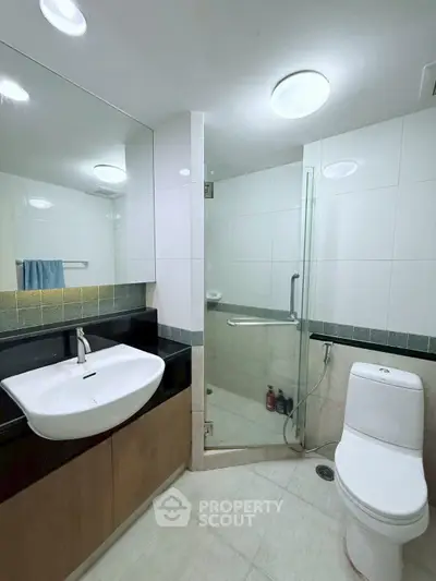 Modern bathroom with glass shower and sleek fixtures in stylish apartment.