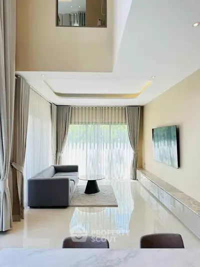 Spacious modern living room with high ceilings and large windows, featuring elegant curtains and a sleek sofa.