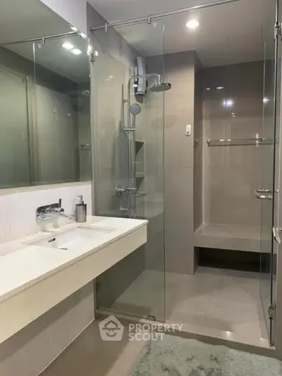 Modern bathroom with glass shower enclosure and sleek vanity in a contemporary home.