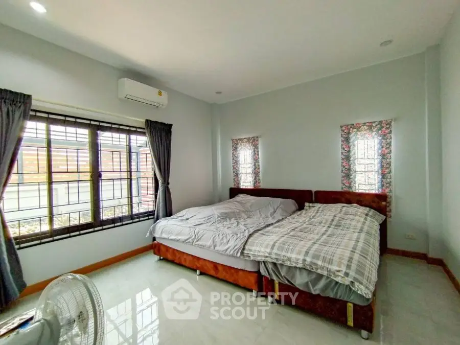 Spacious bedroom with large windows and twin beds, featuring modern decor and natural light.