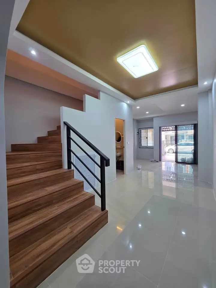 Modern interior with wooden staircase and sleek lighting in spacious living area.