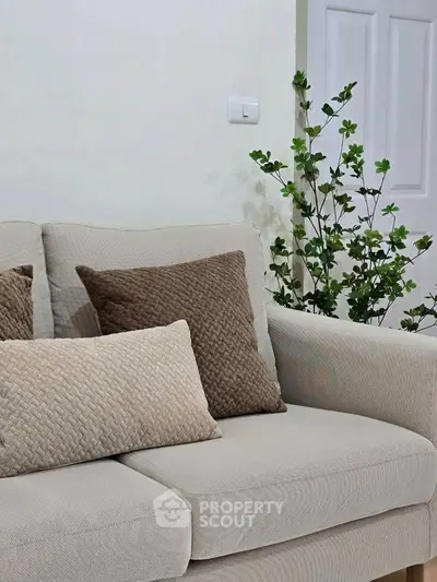 Cozy living room with beige sofa and decorative pillows, perfect for relaxation.