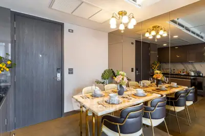 Luxurious dining area with elegant table setting and modern kitchen in open layout apartment.