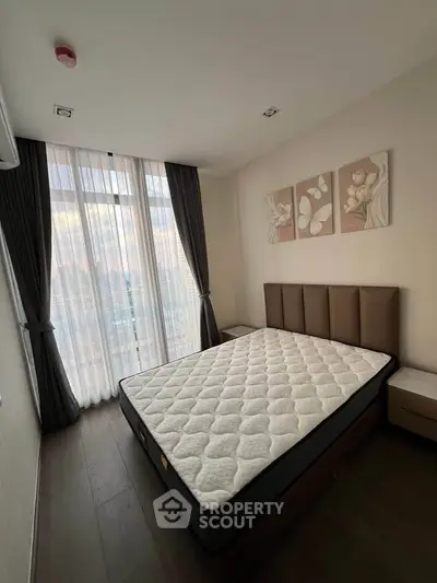 Spacious bedroom with large window and elegant decor in modern apartment.