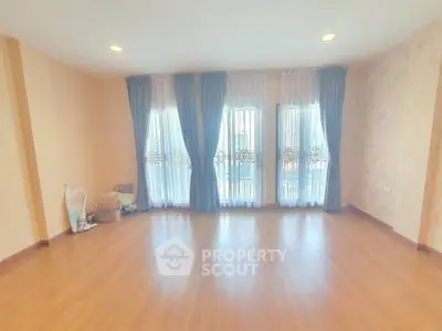 Spacious empty room with elegant curtains and wooden flooring, perfect for customization.