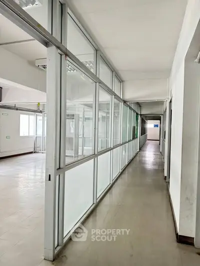 Spacious office corridor with glass partitions and ample natural light