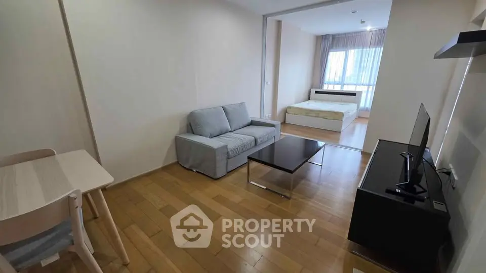 Modern studio apartment with open layout, featuring cozy living area and bedroom with natural light.
