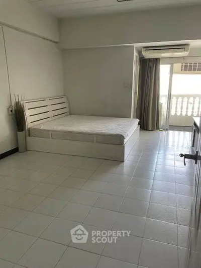 Spacious bedroom with balcony access and air conditioning in modern apartment.