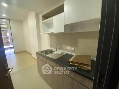 Modern kitchen with sleek cabinetry and stainless steel sink in a contemporary apartment.