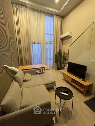 Modern living room with high ceilings, stylish furniture, and large windows for natural light.