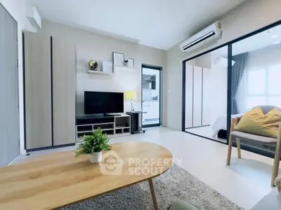Modern living room with sleek furniture and open layout leading to bedroom and kitchen.