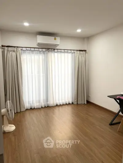 Spacious room with wooden flooring and large windows in modern apartment
