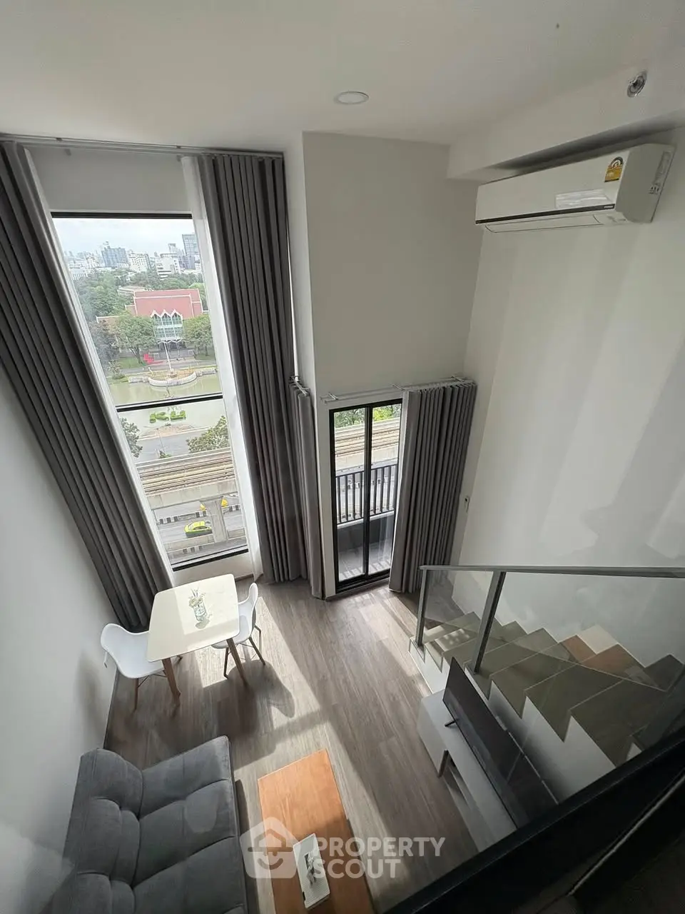 Modern loft apartment with high ceilings and city view from balcony.