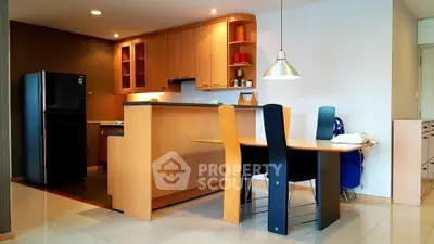 Modern kitchen with open layout and dining area, featuring sleek cabinetry and contemporary lighting.