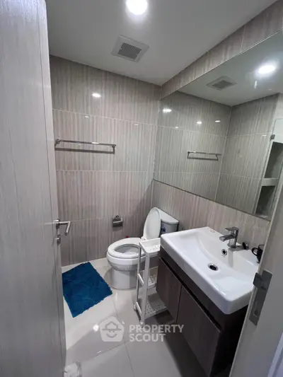 Modern bathroom with sleek fixtures and large mirror in contemporary apartment.