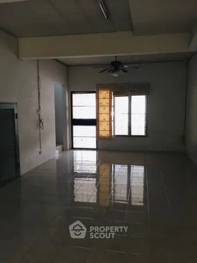 Spacious empty living room with tiled flooring and ceiling fan, ready for customization.