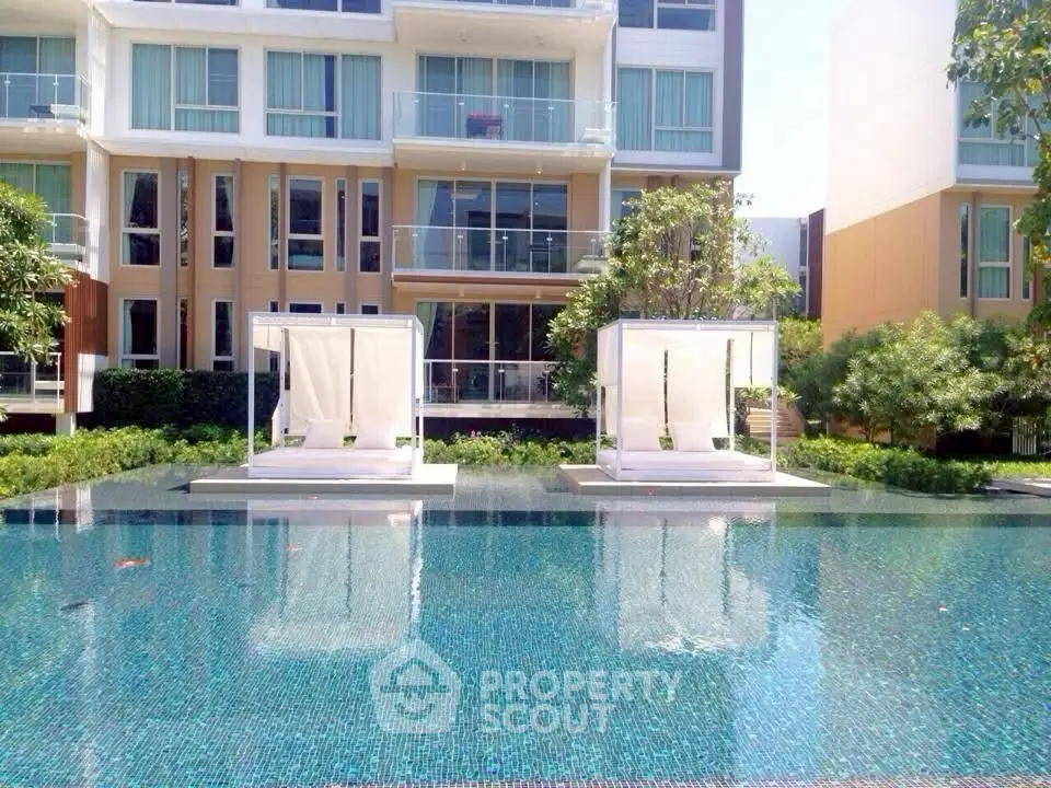 Luxurious apartment complex with stunning poolside cabanas and lush greenery.