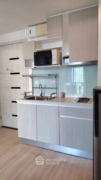 Modern compact kitchen with sleek cabinetry and built-in appliances in a stylish apartment.