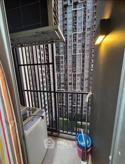 Compact balcony with washing machine and city view in modern high-rise apartment.