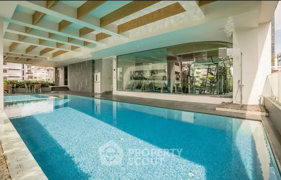 Luxurious indoor swimming pool with modern design and large windows in upscale residential building.