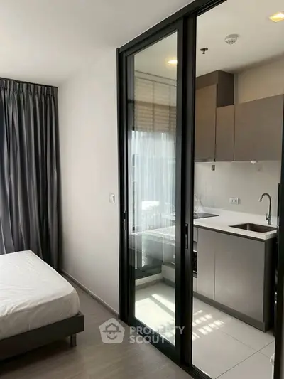 Modern studio apartment with sleek kitchen and cozy bedroom, featuring floor-to-ceiling windows and stylish decor.