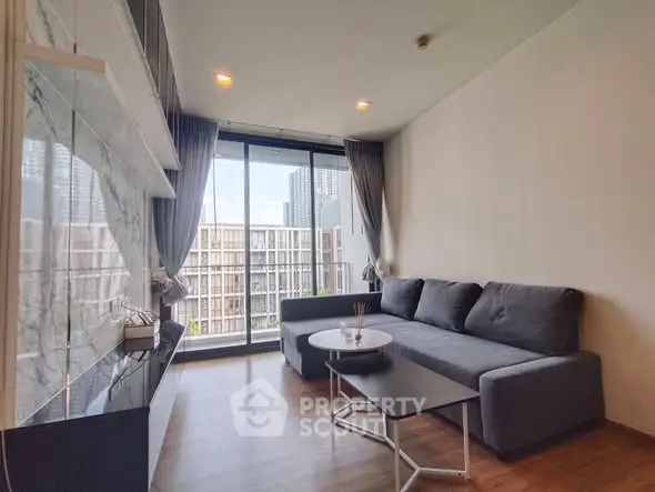 Modern living room with large windows and stylish furniture in urban apartment.