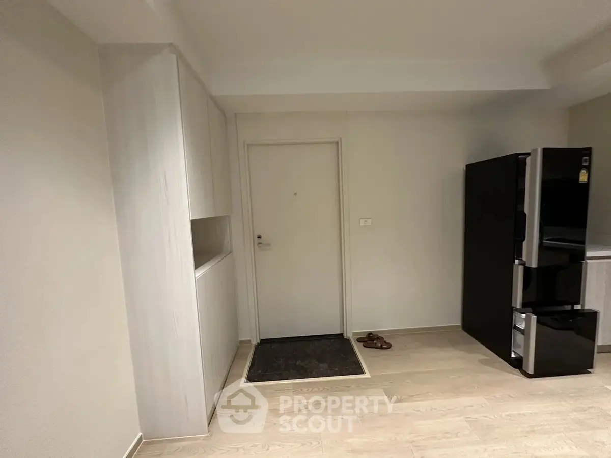 Modern apartment entrance with sleek cabinetry and stainless steel refrigerator