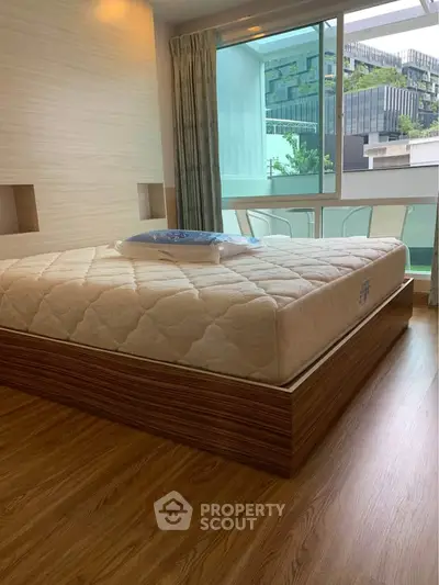 Modern bedroom with large window and stylish wooden flooring
