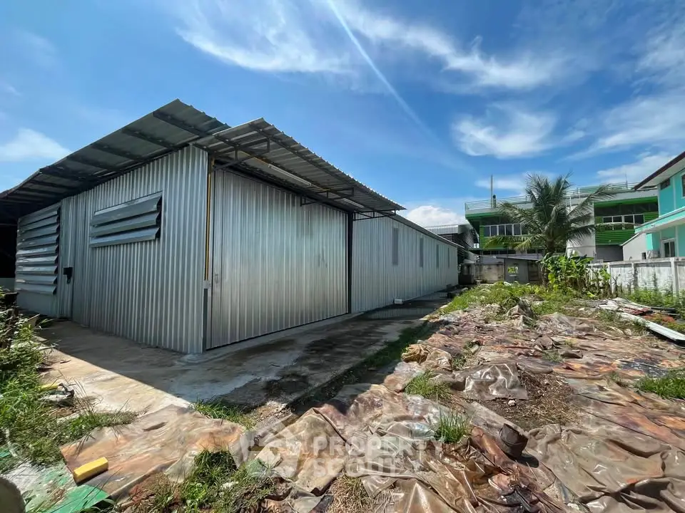 Spacious industrial warehouse with metal siding and ample outdoor space under a clear blue sky.