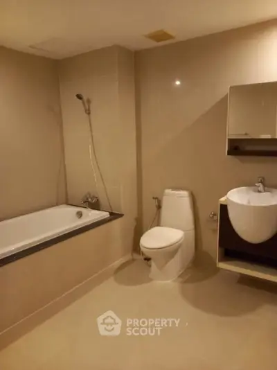 Modern bathroom with bathtub, toilet, and sleek fixtures in neutral tones.