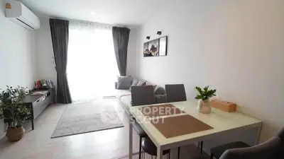 Modern living room with stylish decor and natural light, featuring a cozy sofa and dining area.